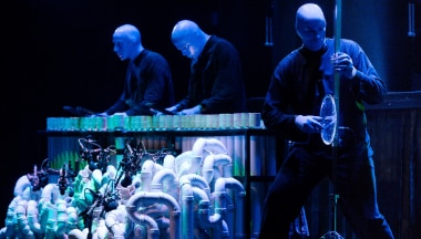 Blue Men tocando instrumentos en el escenario