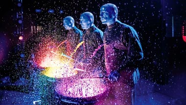 Blue Men usando tambores de pintura coloridos
